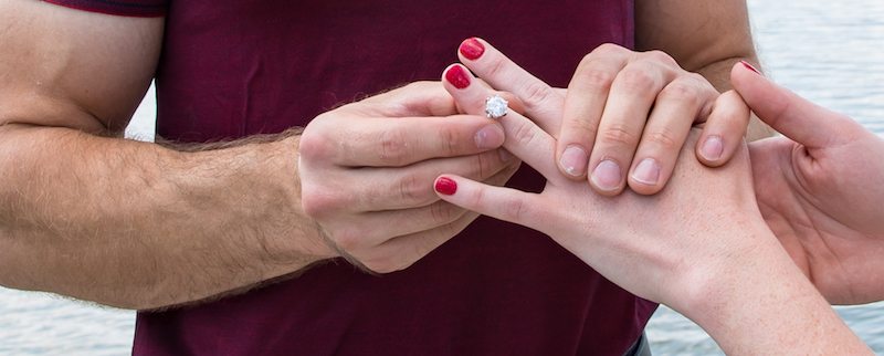 Groom putting engagement ring on finger