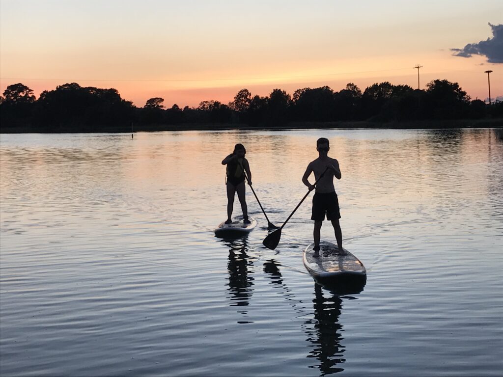 guests paddleboarding at sunset