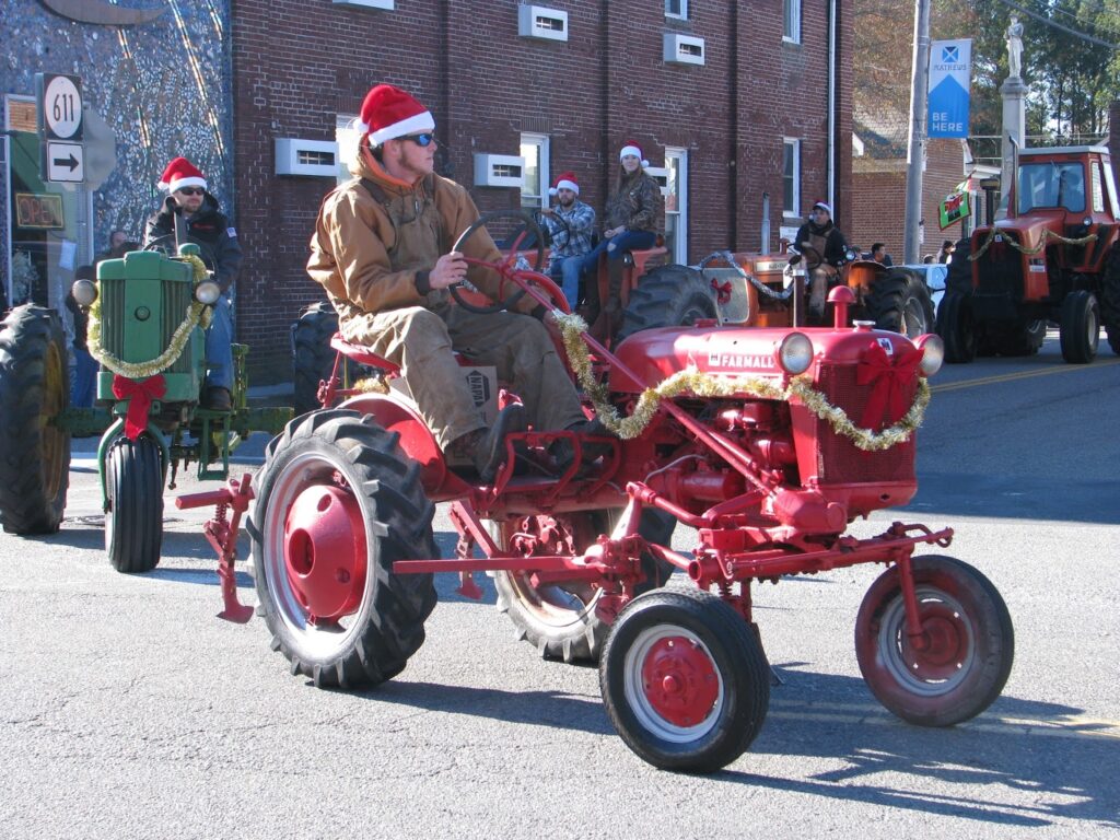 Bubba Christmas, guy driving tractor with coveralls and Santa hat.