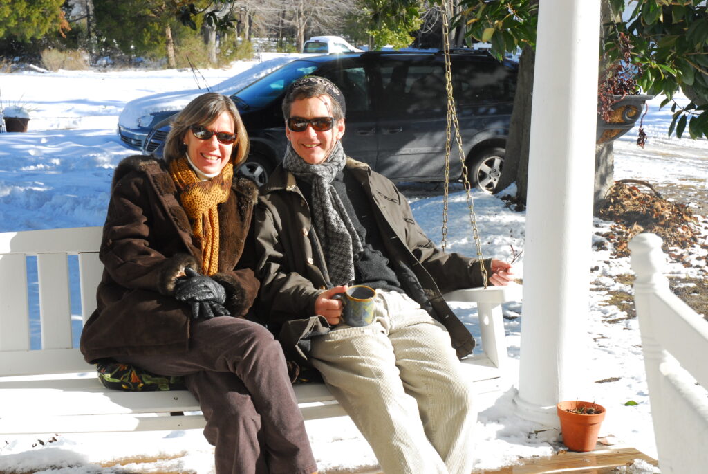 Couple on front porch swing, with snow on the ground.