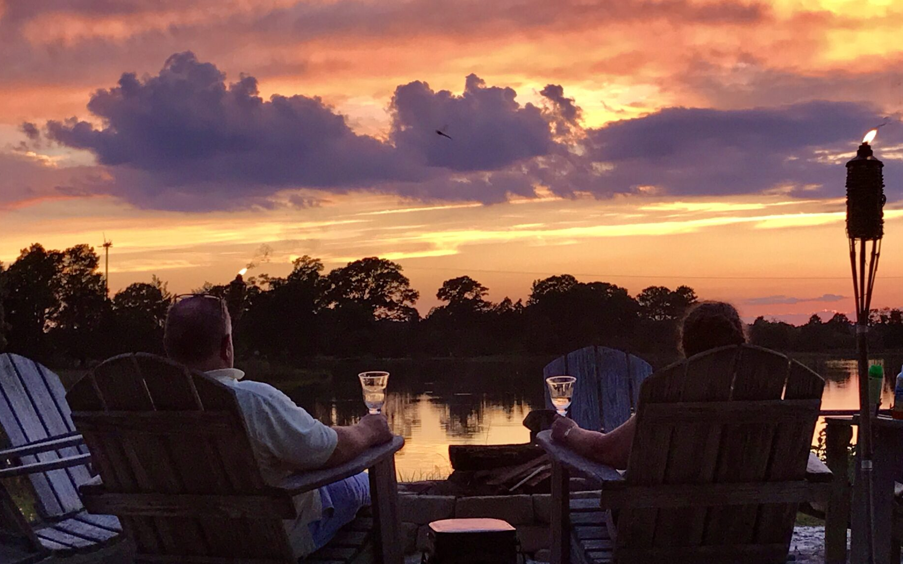guests enjoying wine by the creek during sunset