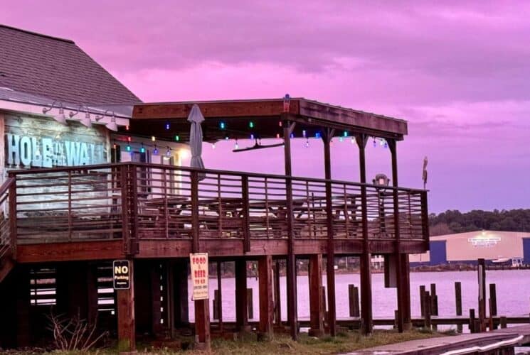 Outdoor deck and patio of a restaurant near a dock and water at sunset