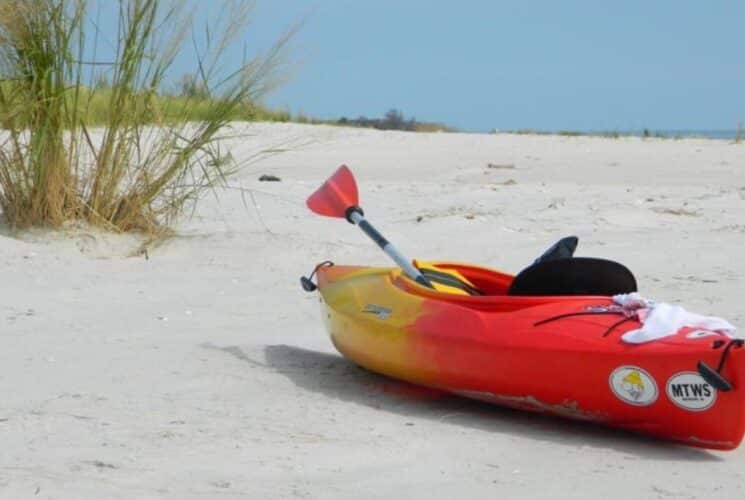 Red and yellow single kayak on white sandy beach