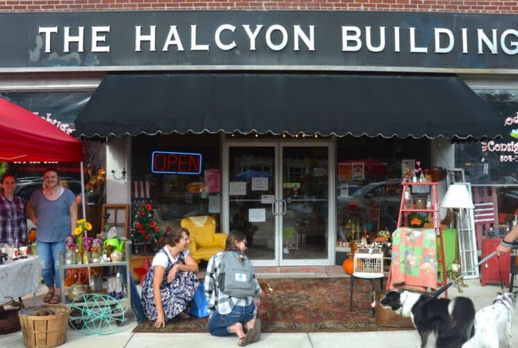 The front of a store with several people stopping to look at wares that are set up out front