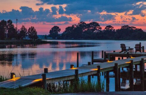 Dock illuminated with lights with calm water in the background at dusk