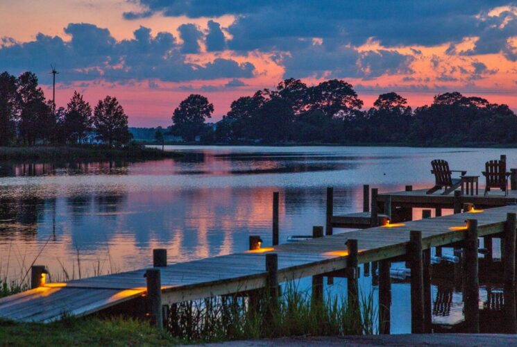 Dock illuminated with lights with calm water in the background at dusk