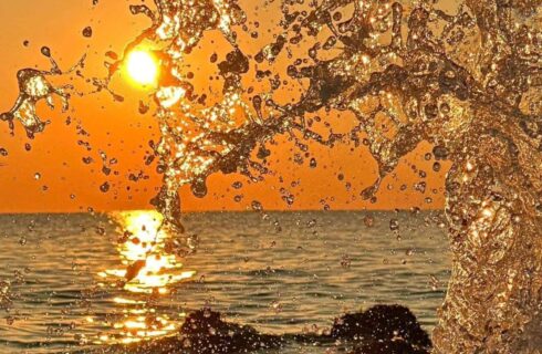 Close up view of water splashing from a wave with the sun in the background