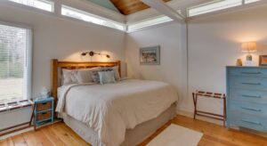 Bedroom with white walls, white trim, hardwood flooring, wooden headboard, and blue dresser