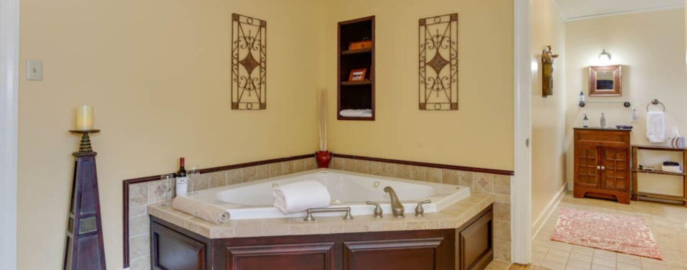 Bedroom with yellow walls, white trim, hardwood flooring, and soaker tub in the corner of the room