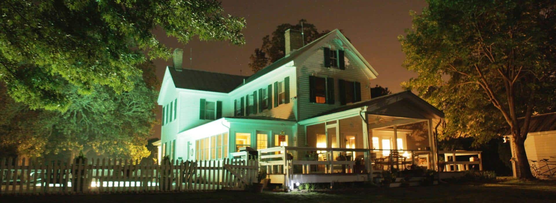 Exterior view of property lighted up at night surrounded by green trees