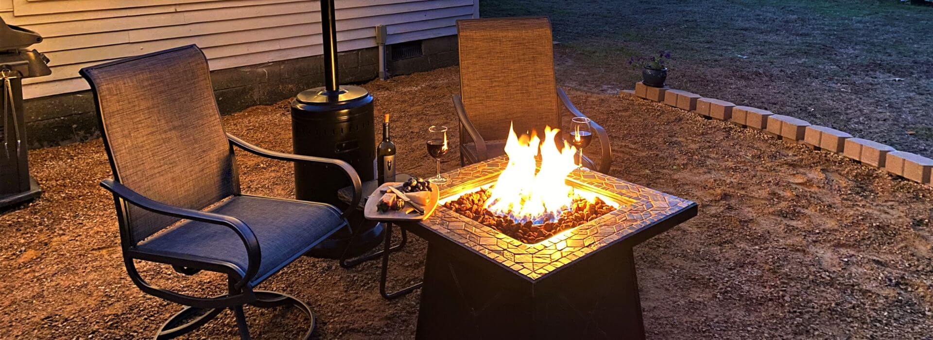 Two patio chairs next to a lighted square fire pit