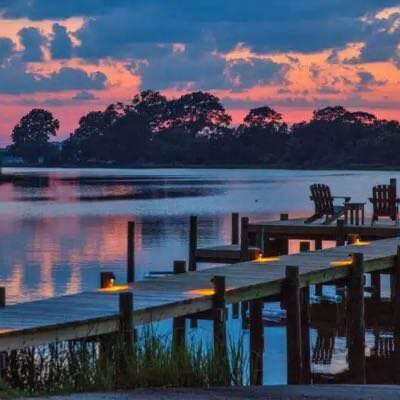 Dock illuminated with lights with calm water in the background at dusk