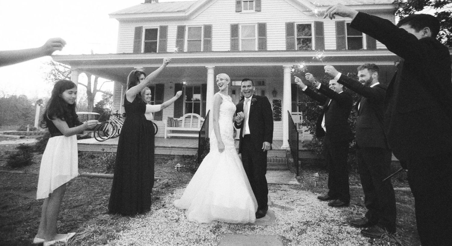 Bride and groom walking down a gravel path surrounded by people holding sparklers