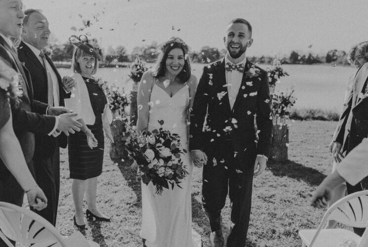 Bride and groom walking while people shower them with rose petals